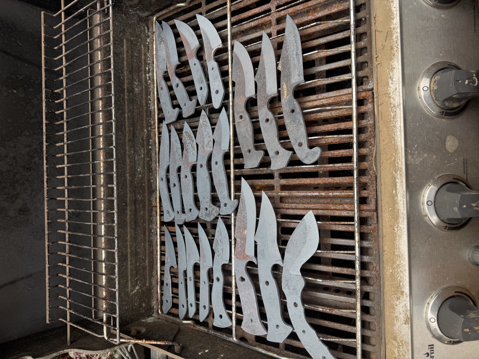 A large batch of shaped knife blanks arranged on a metal rack