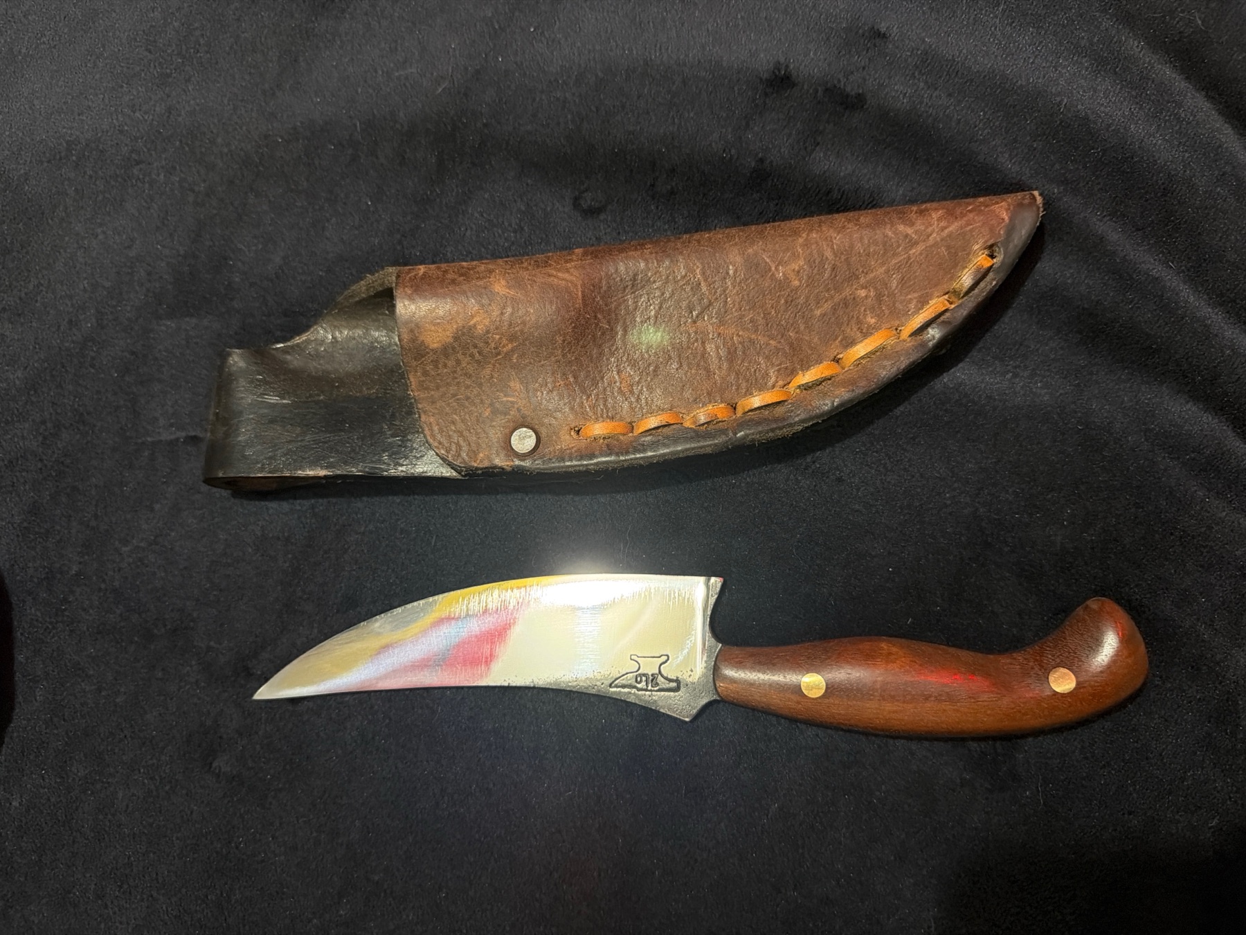 Compact handmade Tulos knife with a curved wood handle beside its brown leather sheath