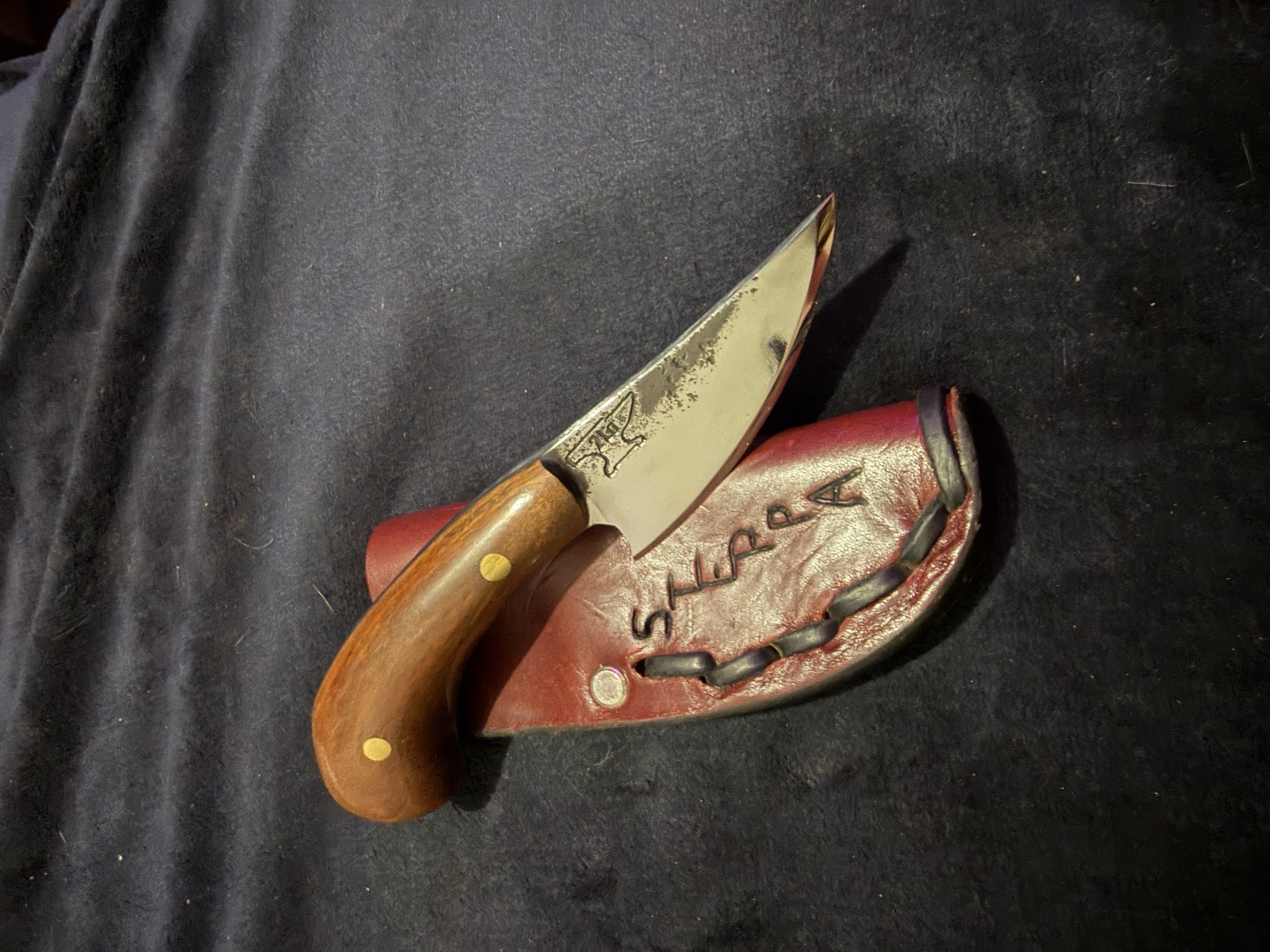 Compact handmade Tulos knife beside a red leather sheath
