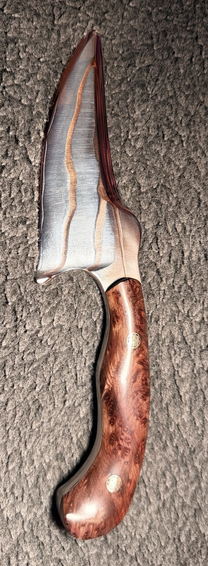 Reverse profile of a Tulos knife showing copper blade lines and a curved burl wood handle