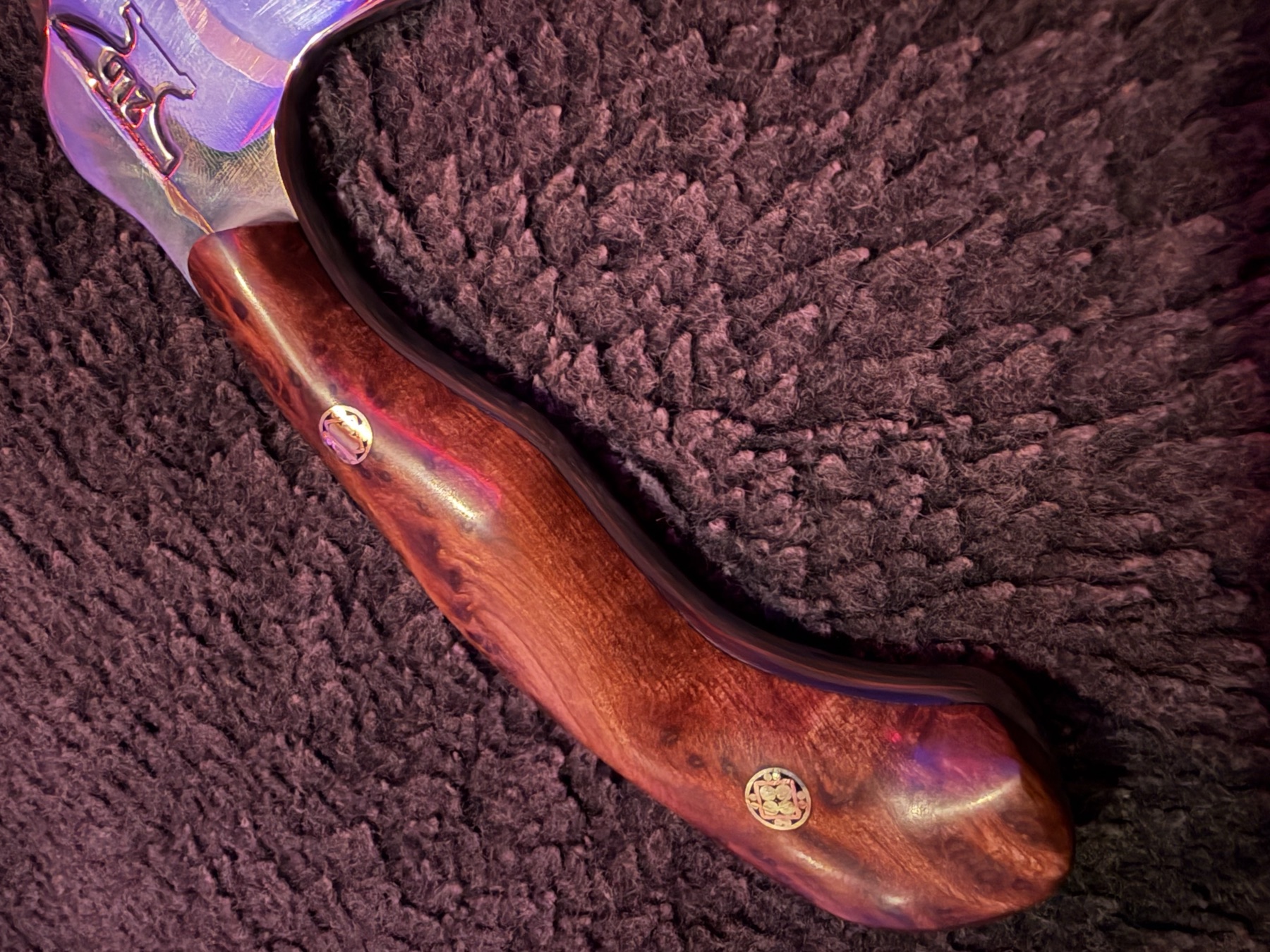 Close detail of the burl wood handle and decorative pins on a Tulos knife