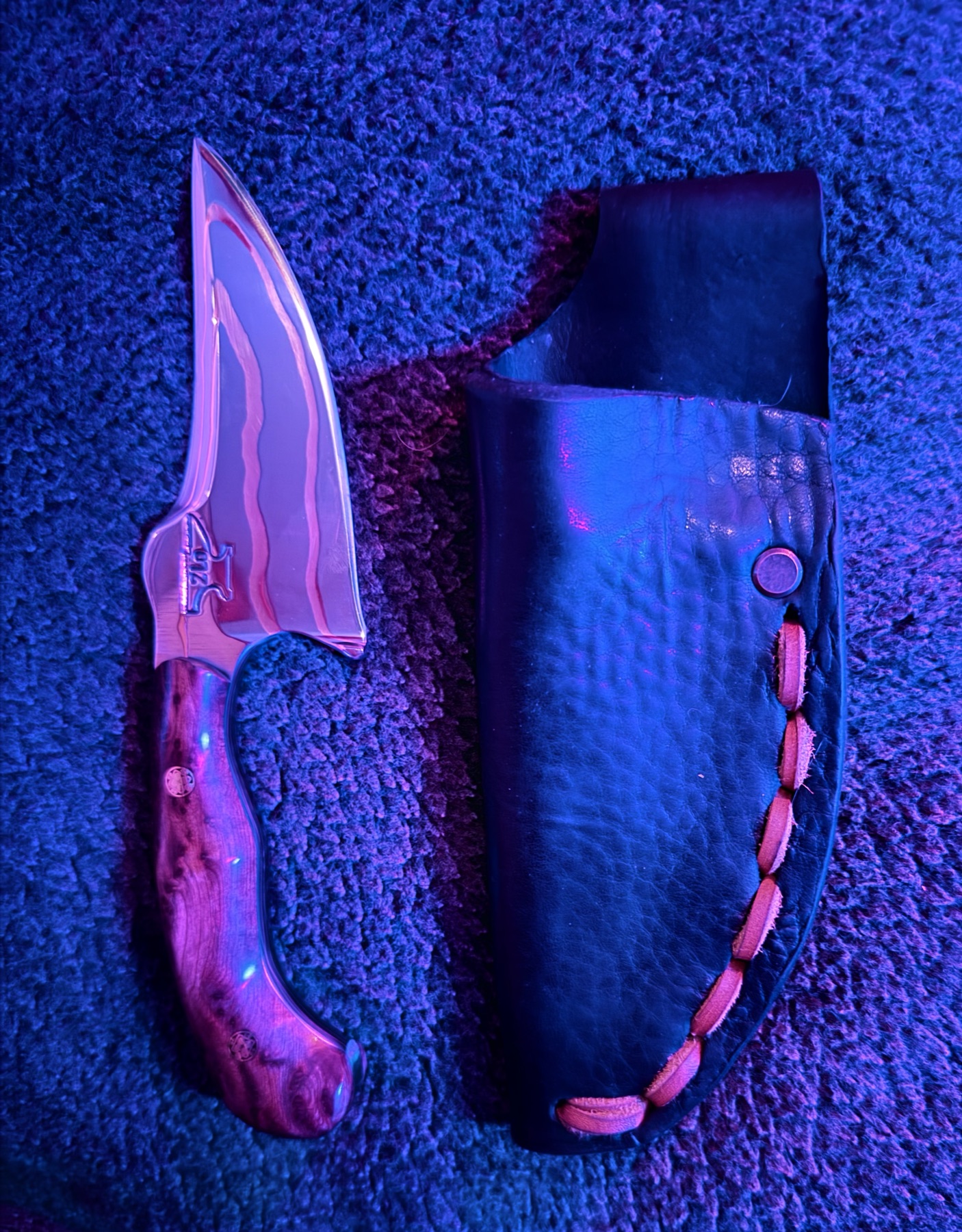 Copper-inlay Tulos knife and leather sheath under blue and magenta studio light