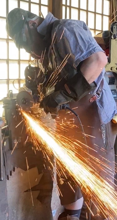 Close workshop view of a bright stream of sparks during blade grinding