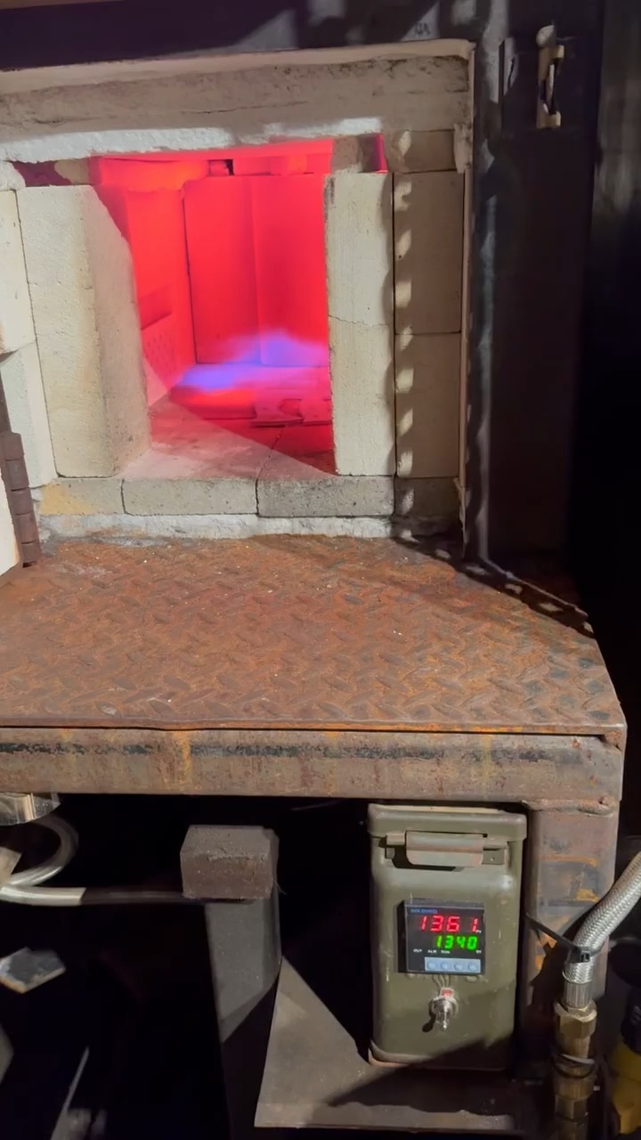 Open heat-treatment furnace glowing red inside the workshop