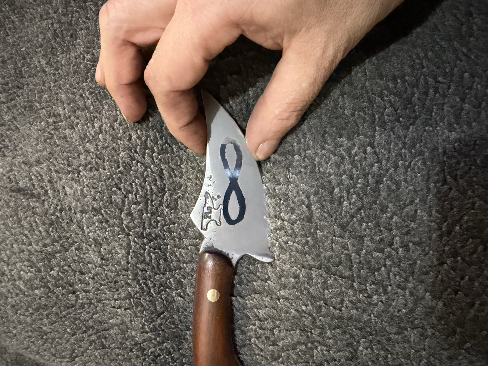 Close detail of an infinity-shaped inlay on a personalized Tulos blade