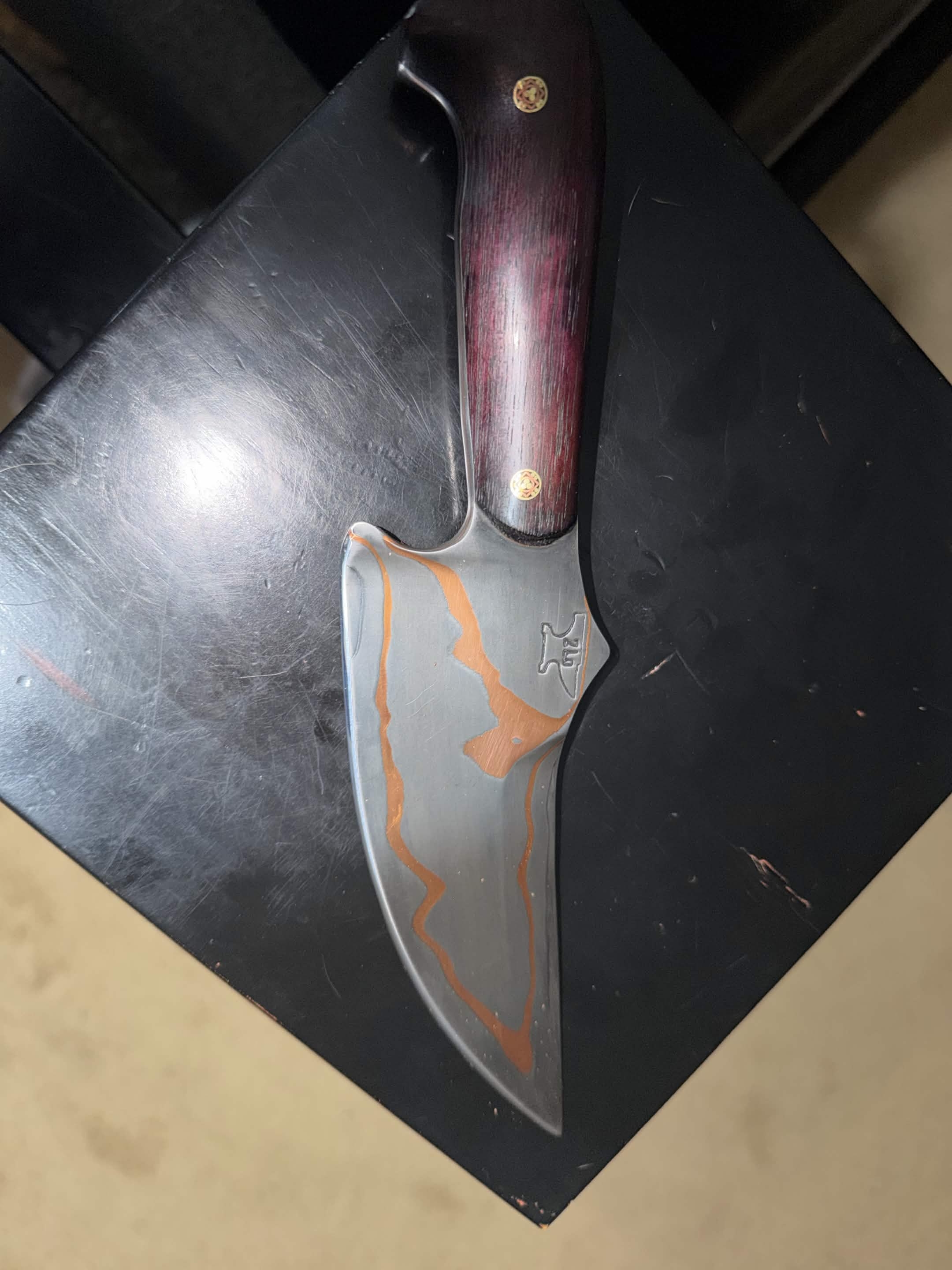 Large handmade Tulos knife with a dark wood handle and copper map-like inlay across the blade