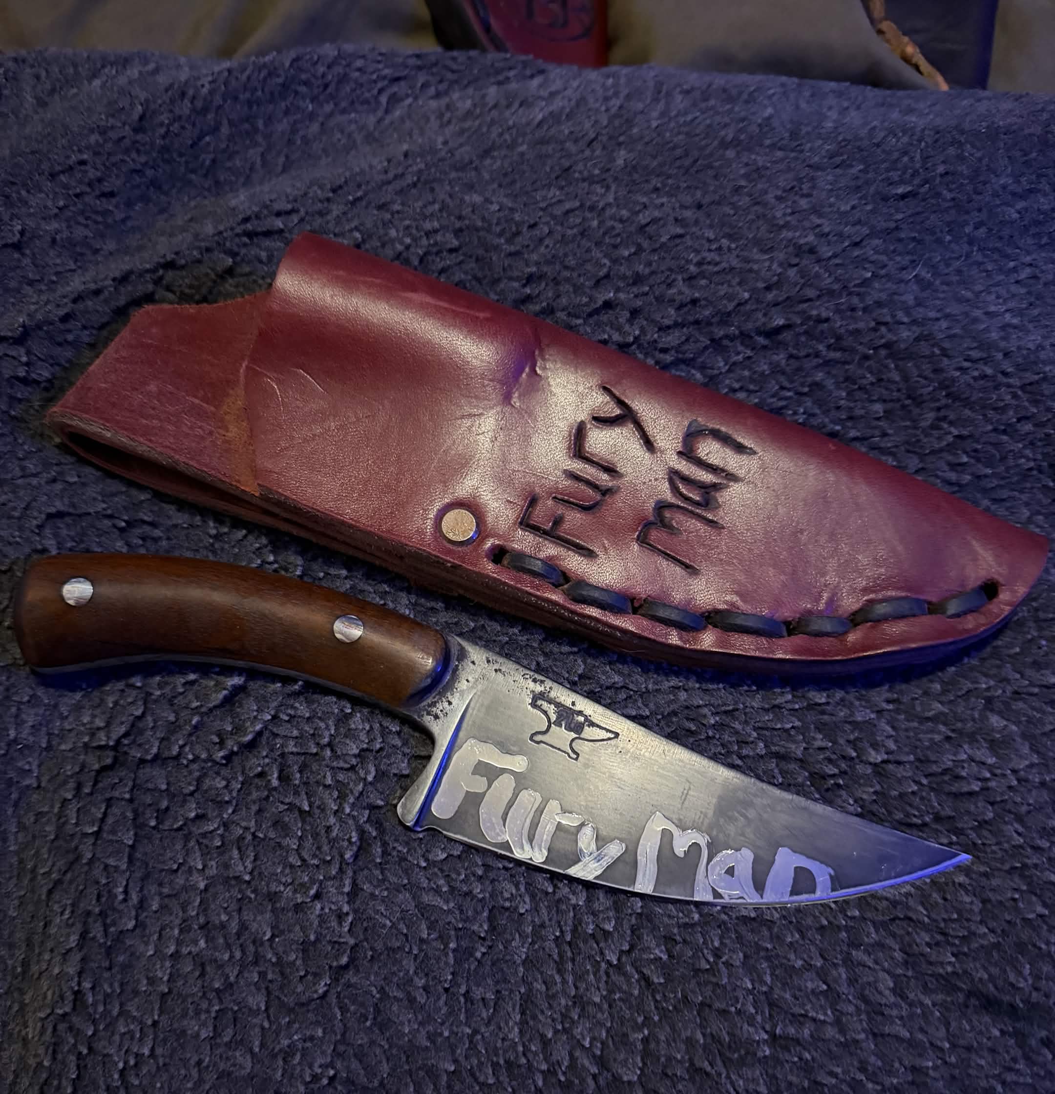 Custom Tulos knife engraved Fur Ma beside its burgundy leather sheath