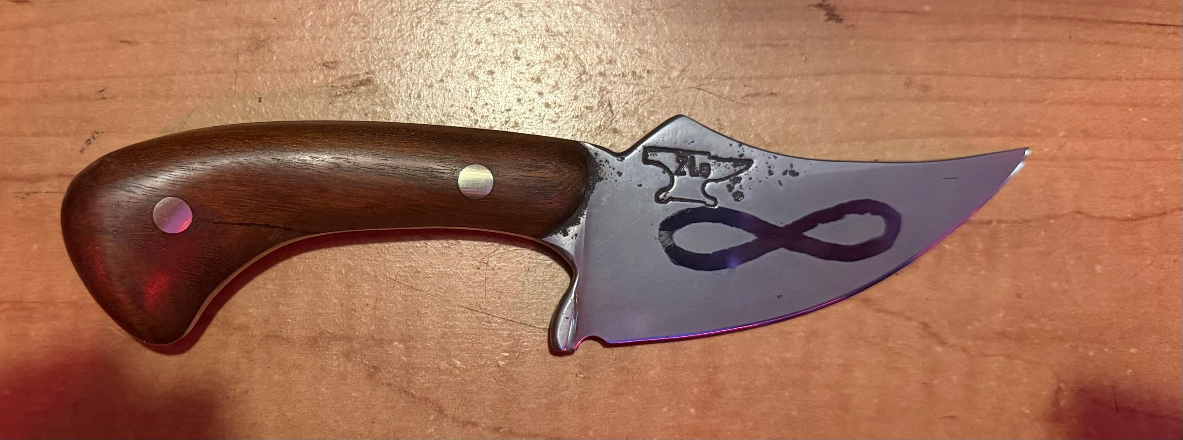 Handmade Tulos knife with a curved wood handle and infinity mark on the polished blade