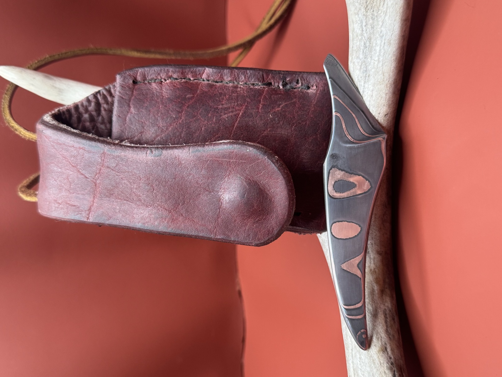 Small copper-inlay Tulos knife hanging beside its fitted sheath