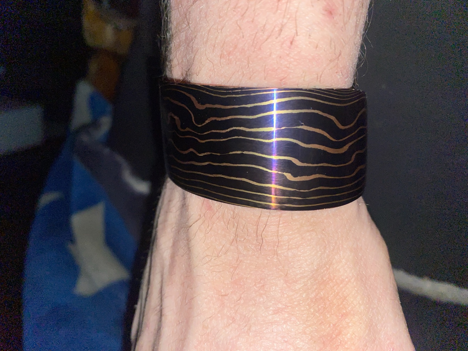 Dark patterned-steel cuff with flowing copper-toned lines