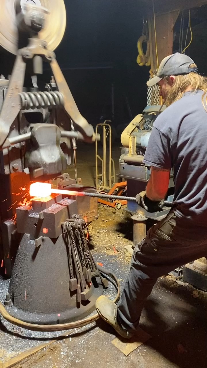 Hot steel being worked under a power hammer in the forge
