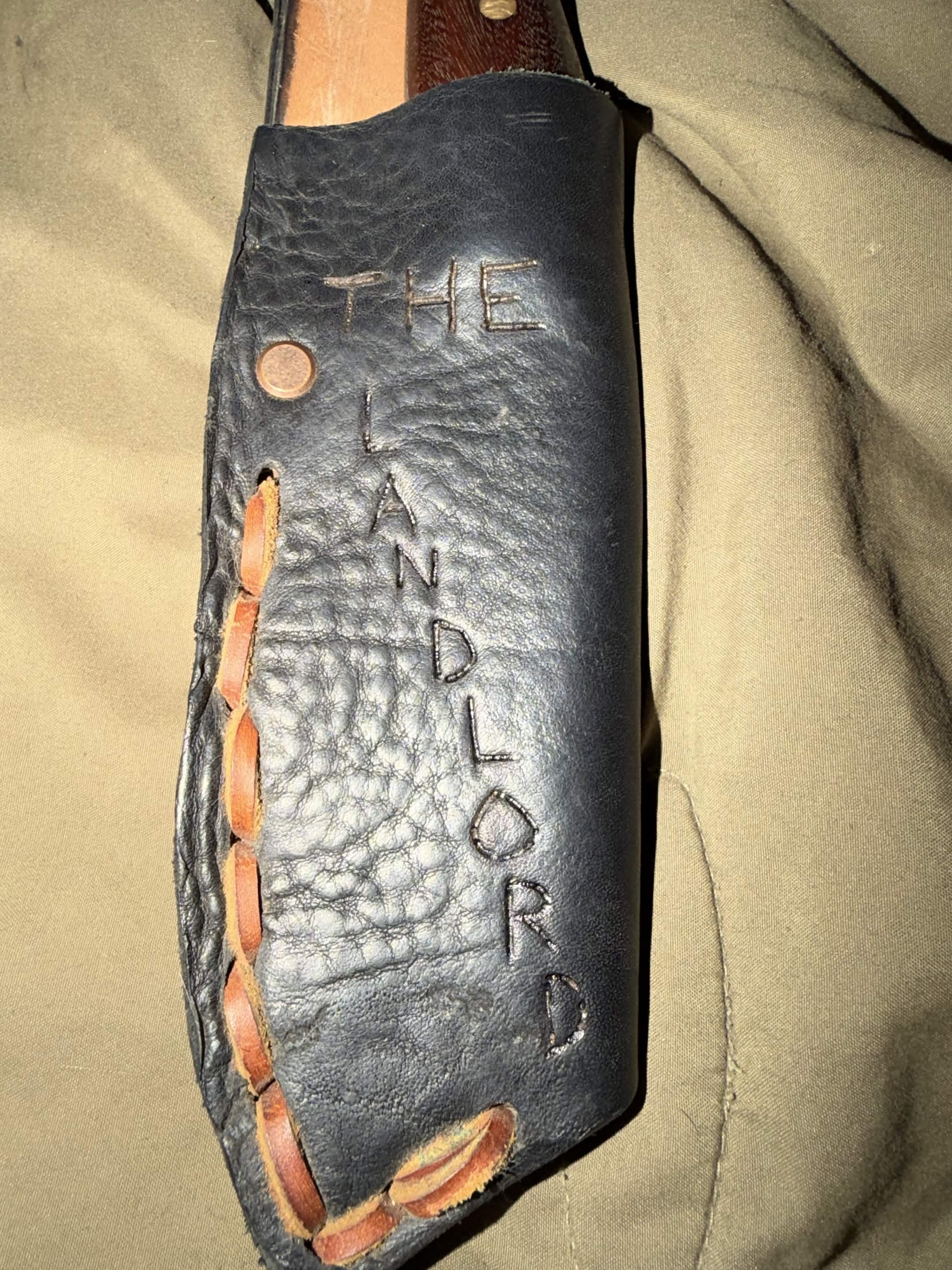 Black handmade leather sheath stamped The Landlord with tan lacing